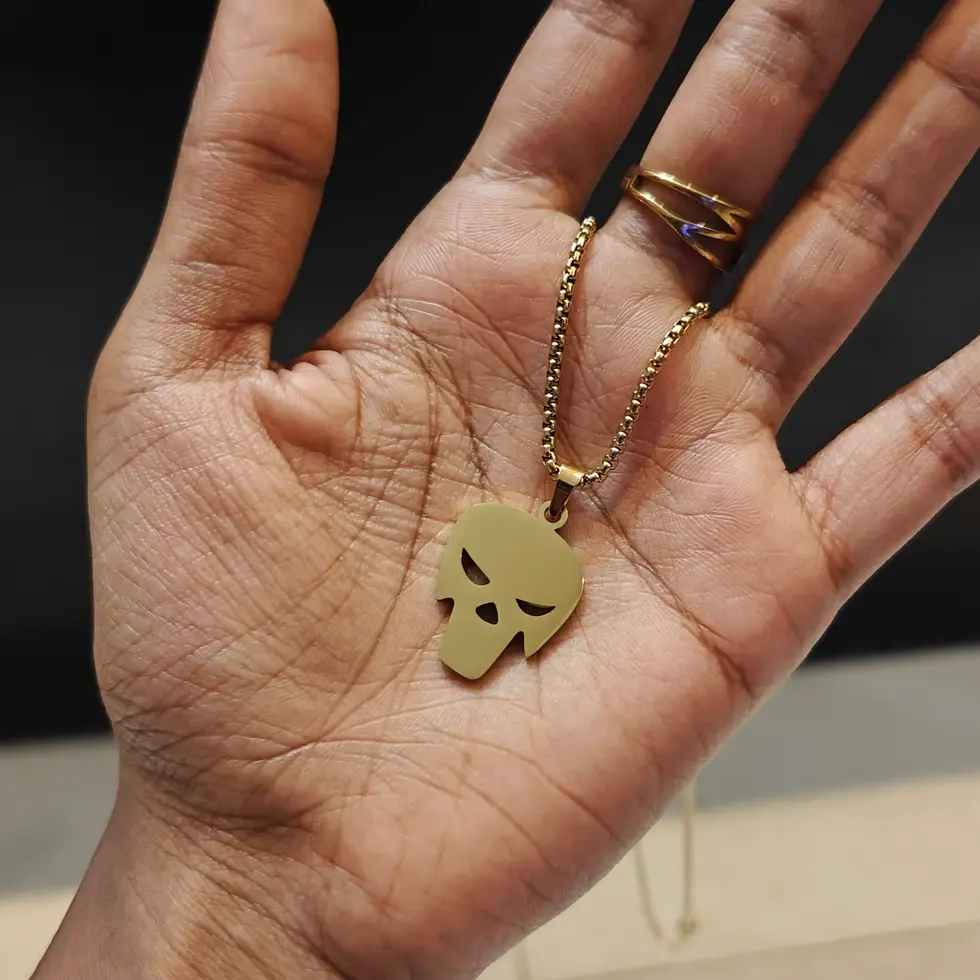 Long gold-tone men's skull pendant necklace featuring a sleek minimalist skull design on a matching chain.