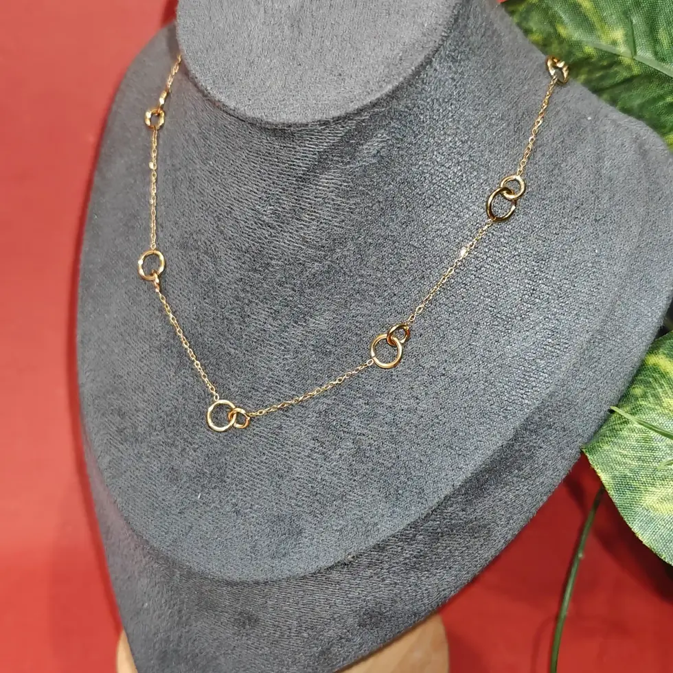 Minimal gold necklace featuring abstract circular and twisted ring charms spaced elegantly along a delicate chain.