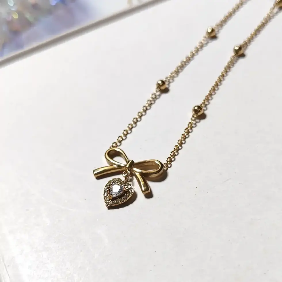 Gold bow pendant with tiny heart and white stone
