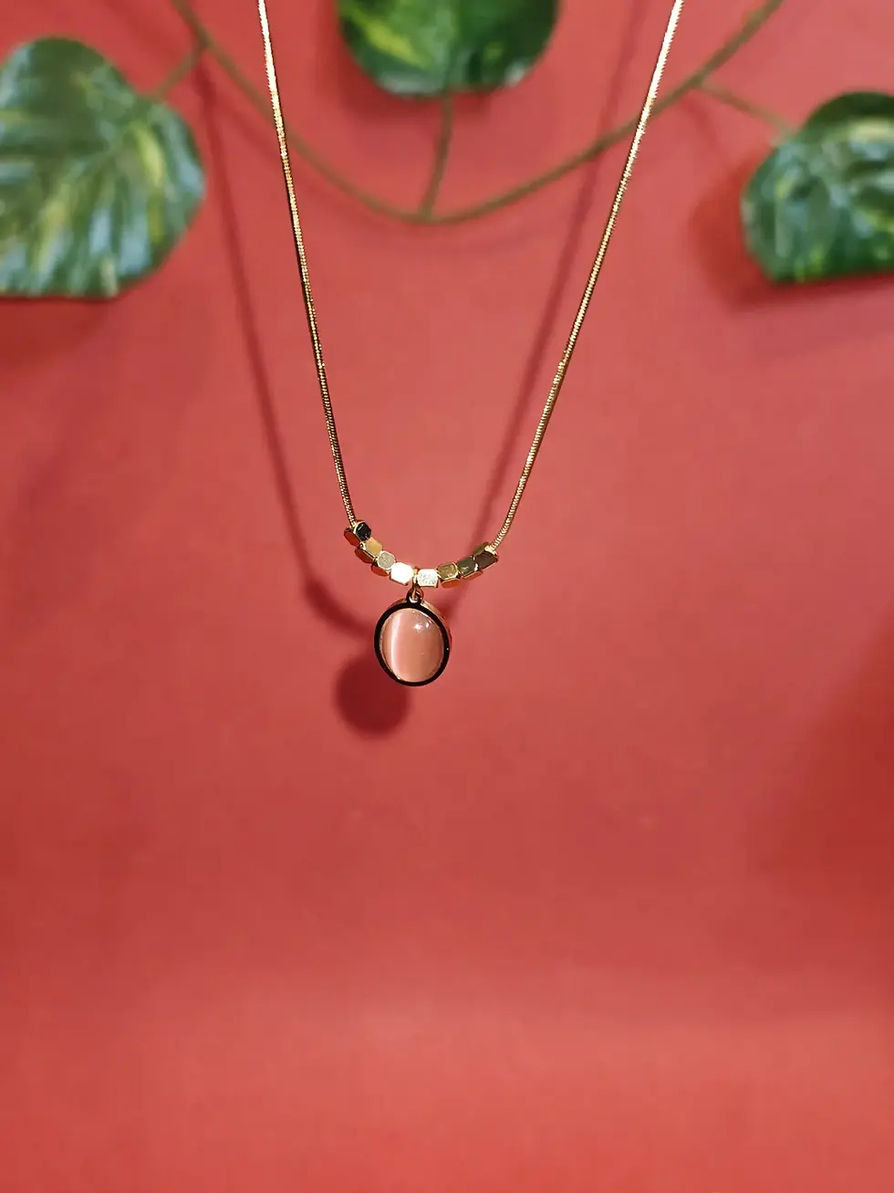 Elegant layered gold necklace featuring black bead accents and an oval black pendant charm on a delicate chain.