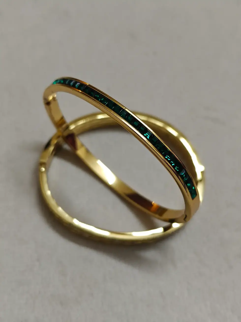 Slim gold baby bracelet featuring a fine green stone channel detail.