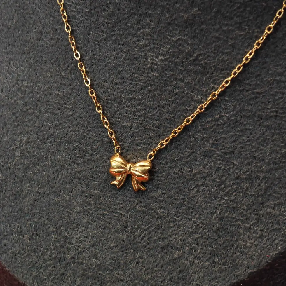 Gold-toned necklace with a small bow-shaped pendant on a delicate chain.