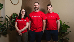 Sygaldry founding team wearing branded red shirts in office setting with plants