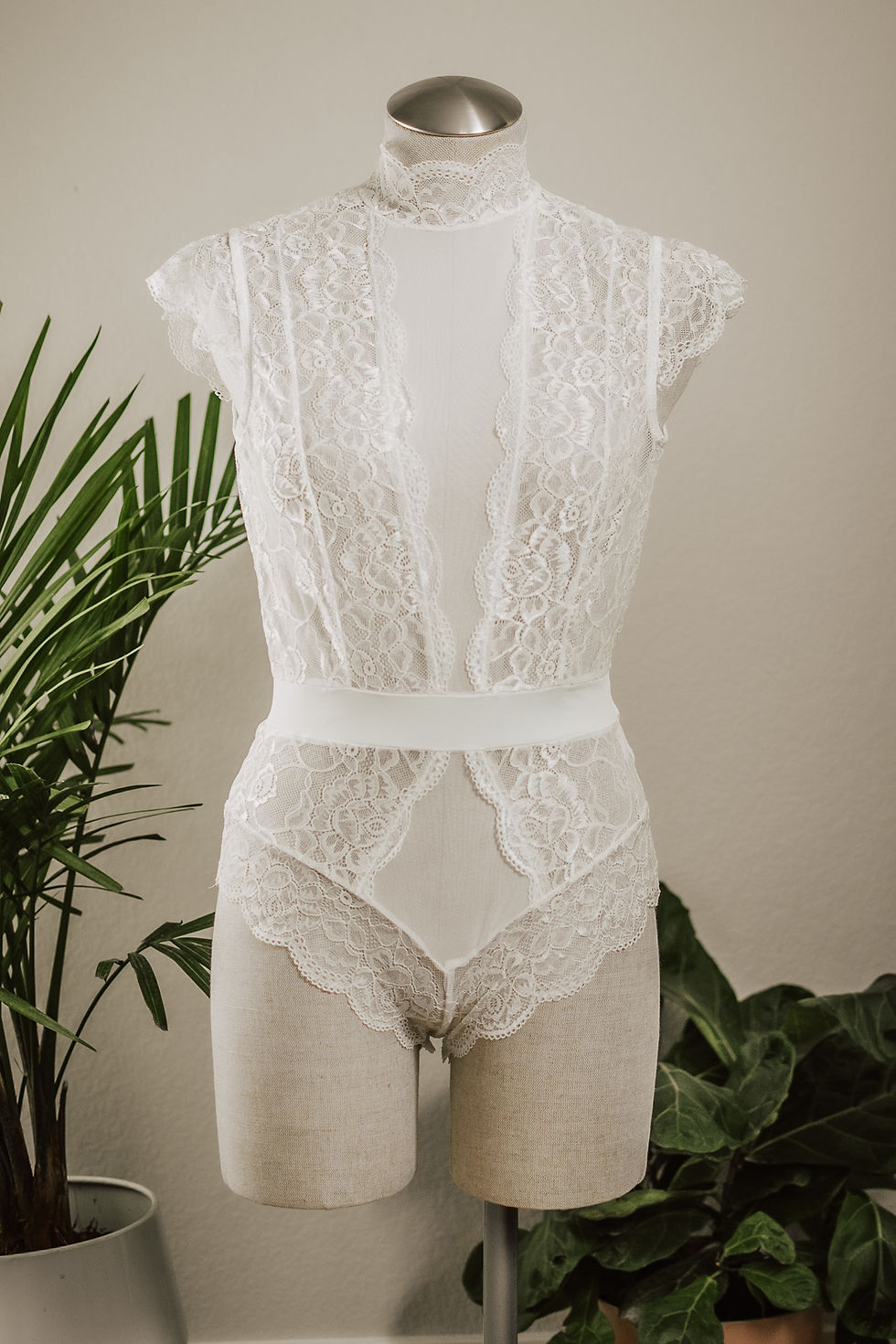 White lace bodysuit on a mannequin, Large Lace Bodysuit Black, with soft background.