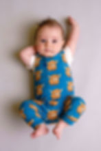 A baby wearing a highland cow print dungaree romper - Simpson + C handmade children's clothing.