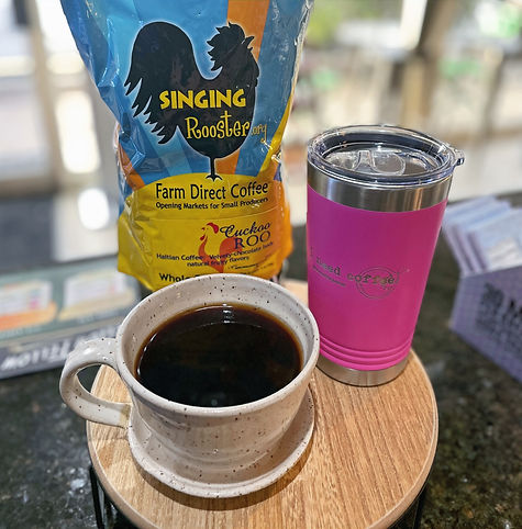 	Cup of freshly brewed coffee next to a bag of Haitian coffee beans and custom I Need Coffee Jupiter cup