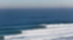 High-resolution view of blue ocean swell lines and breaking waves at a coastal surf break under a clear sky