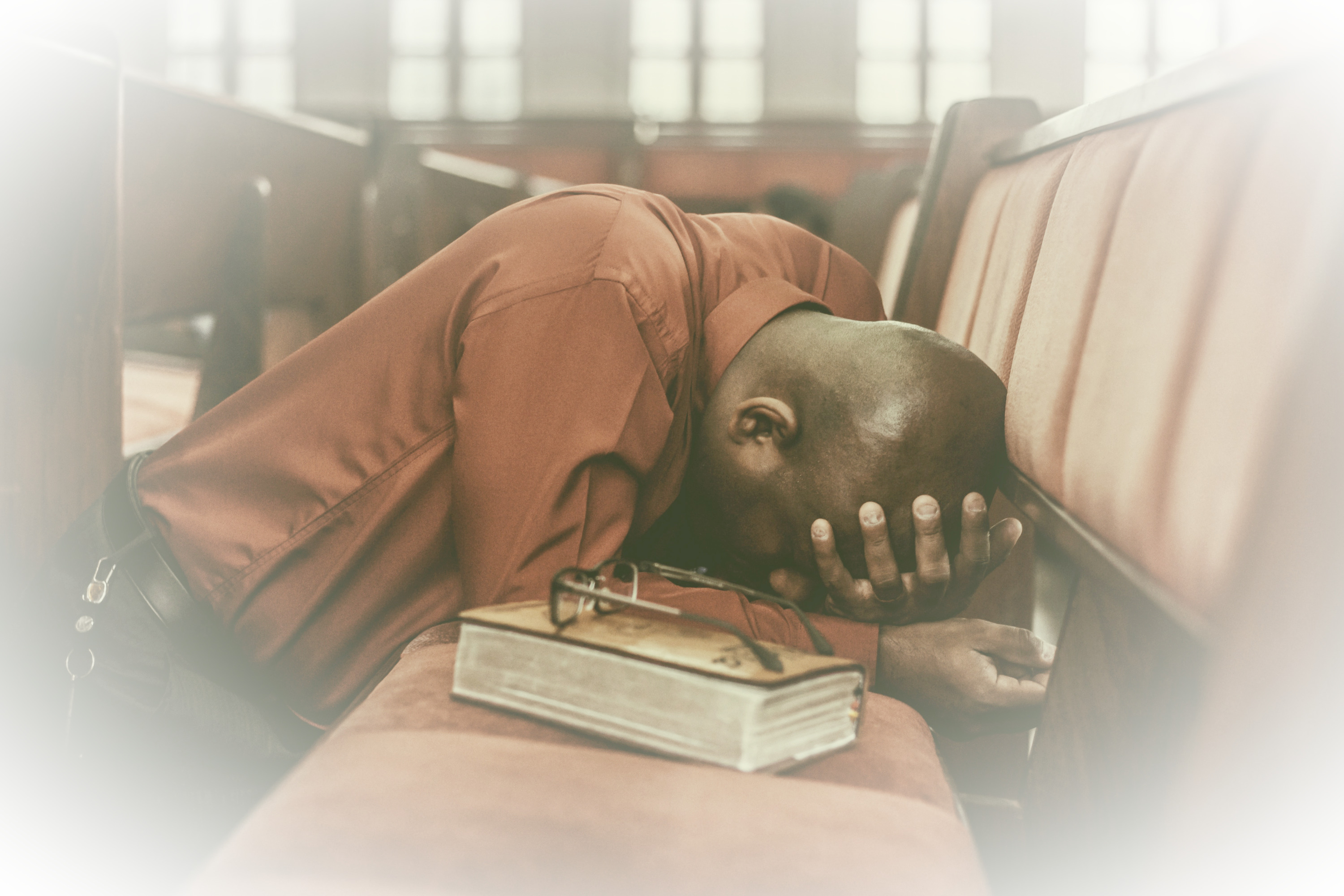 adult man kneeling deep in prayer in church