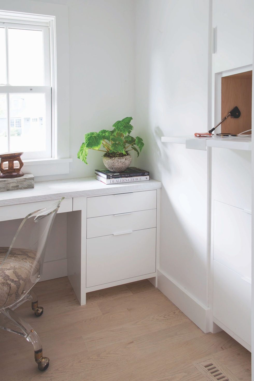 a white desk with a book on top of it, and a ceramic chair
