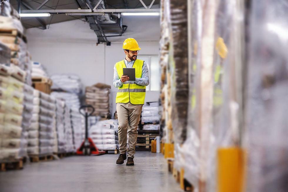 Arbeiter in Sicherheitsweste geht durch Lager, Tablet in der Hand