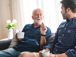 Older father talking with his adult son at home, representing family legacy planning and the transfer of wealth across generations.