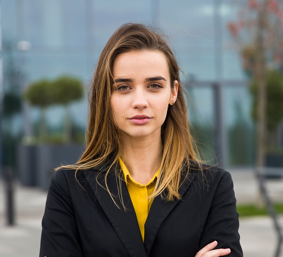 Young businesswoman stands confidently, arms crossed, yellow shirt, black blazer and smiling