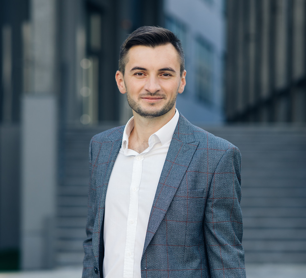 Smiling businessman with hands in pockets, standing in front of a building, About