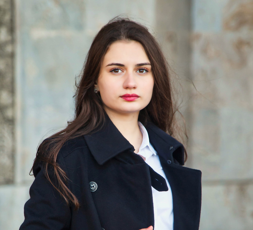 Young woman in black coat and white shirt, looking at camera.