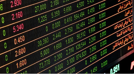 Bright stock market display board showing financial data in green and red with figures and Arabic text on a dark background.