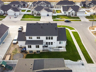 Aerial shot of a residential area in Spanish Fork, Utah, showcasing modern homes and green lawns.