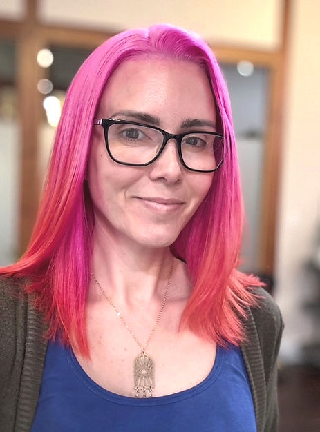 Headshot of Shayna Kirk smiling, bright pink hair and black glasses