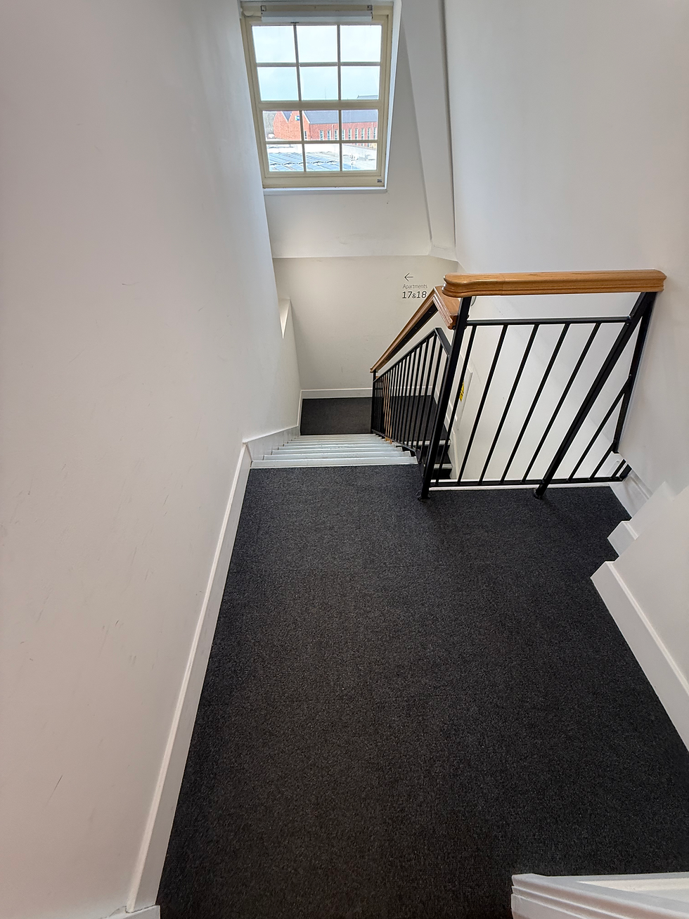 Clean carpeted communal landing with metal railing