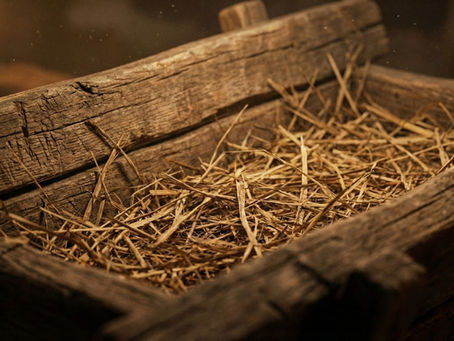 Detalhe de madeira rústica e palha de uma manjedoura, simbolizando a humildade do nascimento de Jesus em Lucas 2.