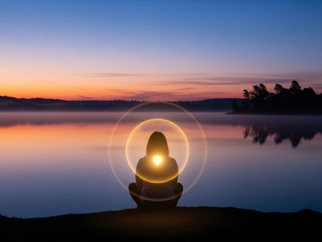 Pessoa em paz à beira de um lago, com uma esfera de luz dourada protetora em volta de seu peito e cabeça.