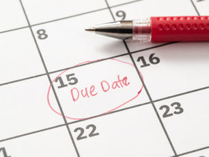 Calendar with a red pen. The 15th is circled with "Due Date" written in red. A sense of urgency is conveyed.