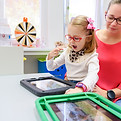 Non-verbal girl living with cerebral palsy, learning to use digital tablet device to commu