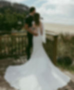 bride with extra long veil with her groom smiling out into the landscape with long curly brown hair