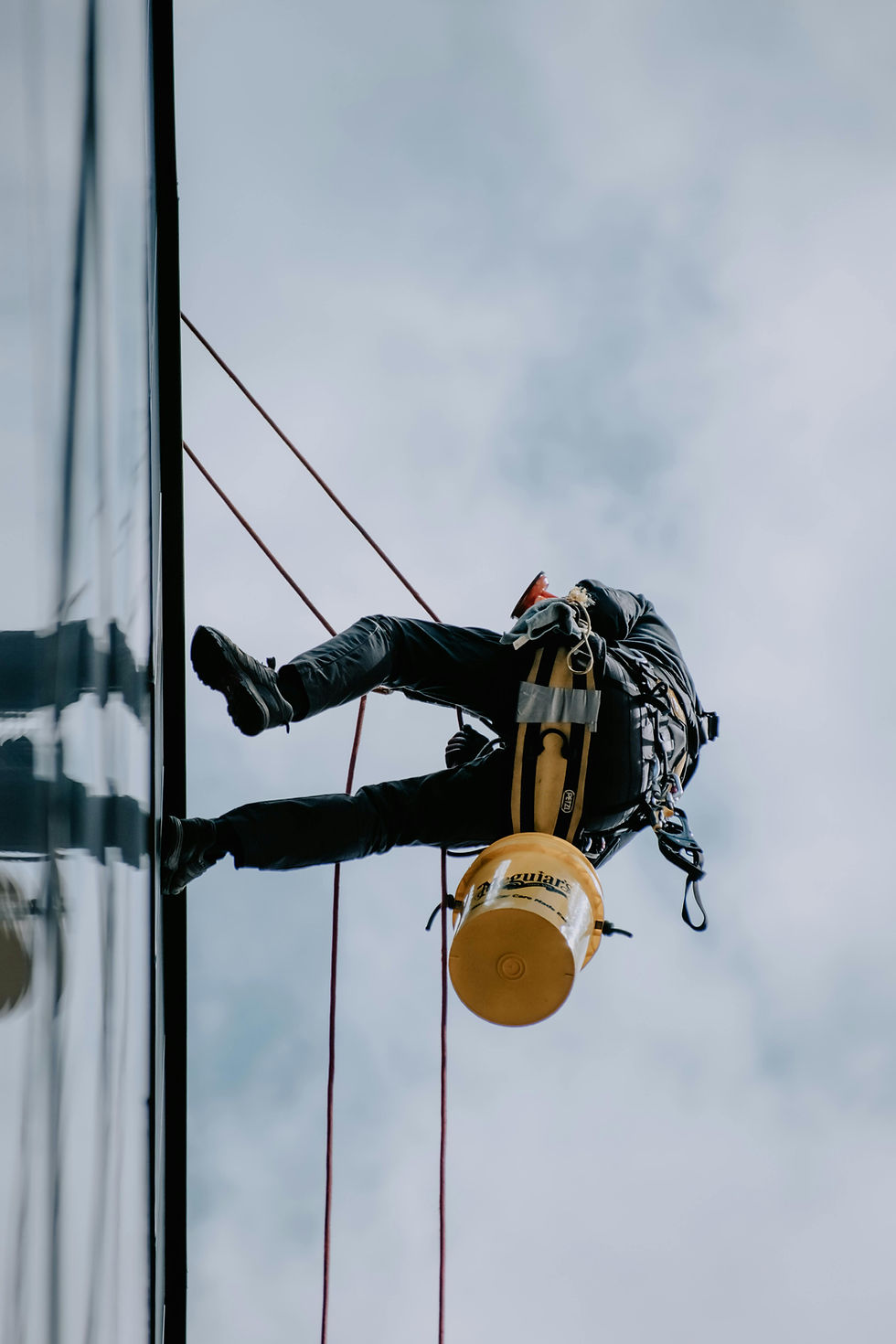 Man scaling modern office building to clean the windows