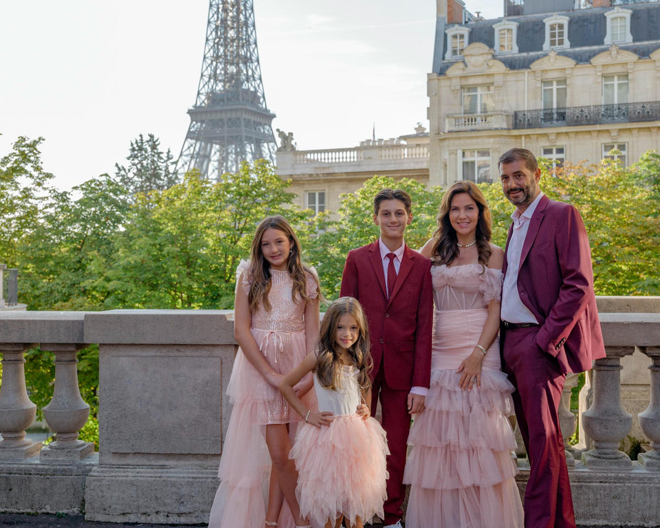 Family of five posing in formal pink attire with Eiffel Tower.