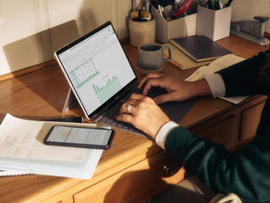 Person working on a laptop at a wooden desk preparing tax return documents