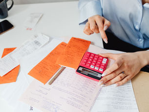 Hands using a calculator at a desk covered with receipts and financial documents