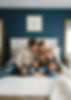 Familie mit zwei kleinen Kindern auf einem Bett sitzend