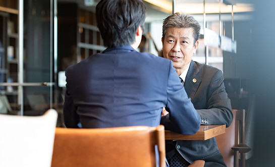 若い職員から相談を受けている上司のシニア男性