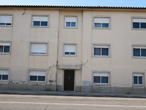 Edifício de três pisos com fissuras diagonais na fachada associadas a possíveis assentamentos diferenciais das fundações.