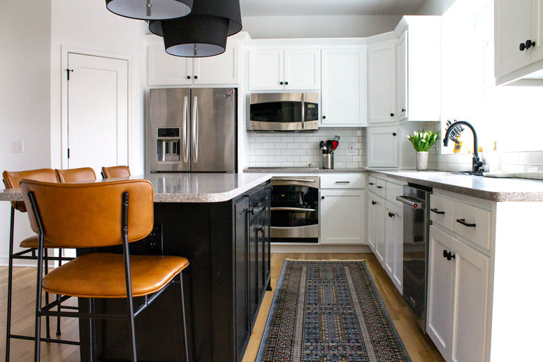 Modern kitchen with stainless steel appliances, white cabinets, and wooden floors.