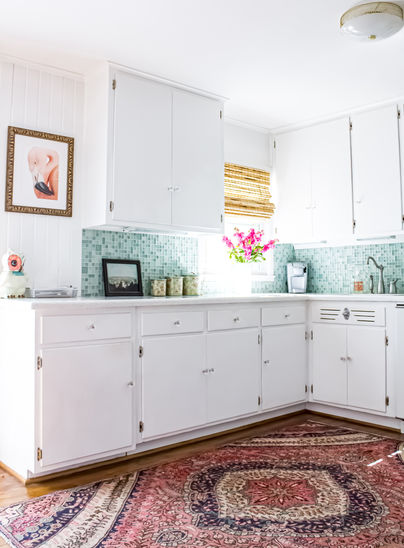 White kitchen cabinets, artwork, and rug. Kitchen design with light and bright Overland Park Home.