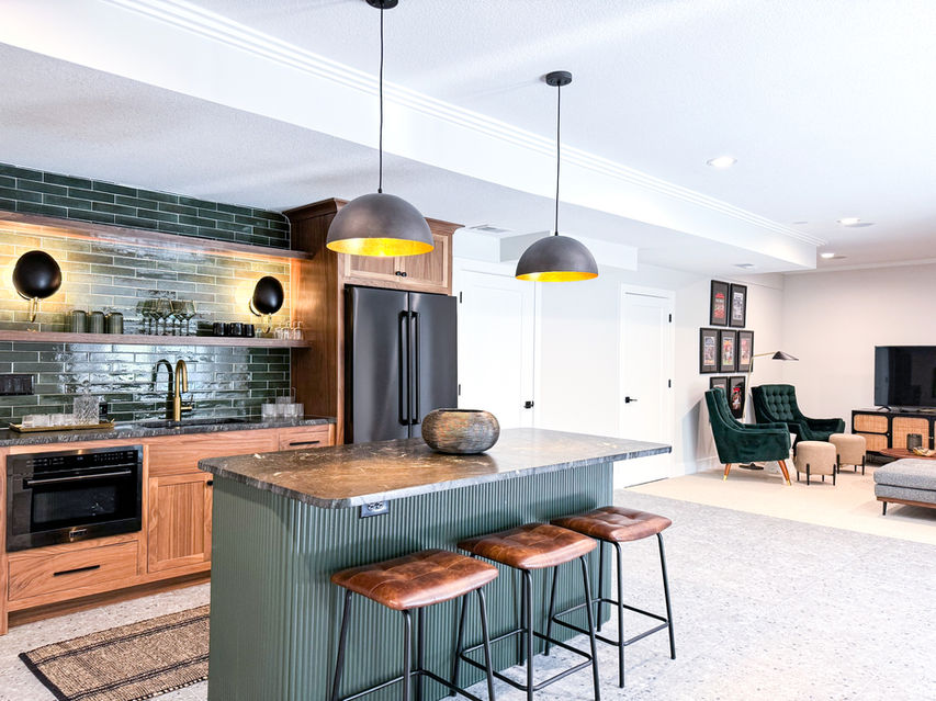 Kitchen island with three stools, green brick backsplash, and pendant lighting.