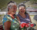 Two women smile while holding bouquets of roses and baby's breath