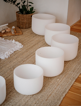 Frosted quartz crystal sound bowls arranged on the floor for acoustic sound healing and meditation.