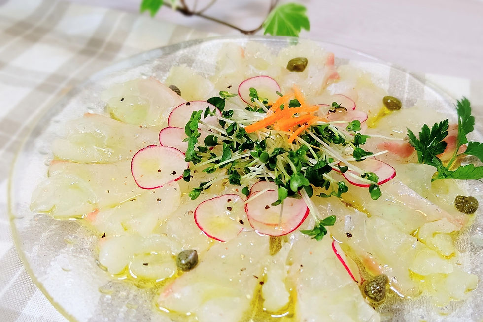 白い皿に薄切りの白身魚のカルパッチョ。ラディッシュと青菜、にんじんが中央に盛られ、爽やかで上品な雰囲気】【。