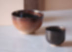 Front View of a minimalist, vibrant earth tone glazed matcha ceremony bowl on a grey counter surface.