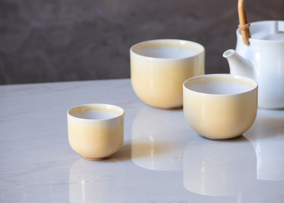 Thumbnail: Front view of three minimalist, round, espresso cups in light yellow and various sizes on a white marble surface.