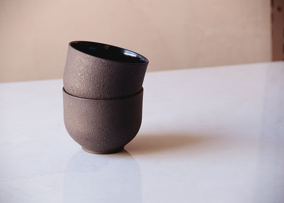 Thumbnail: Two stacked textured dark ceramic bowls sit on a marble surface against a soft beige background.