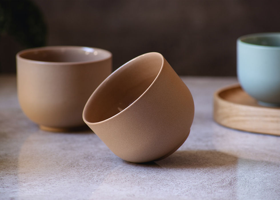 Front view of two round, minimalist, ceramic cappuccino cups in brown and a wooden tray on grey marble.