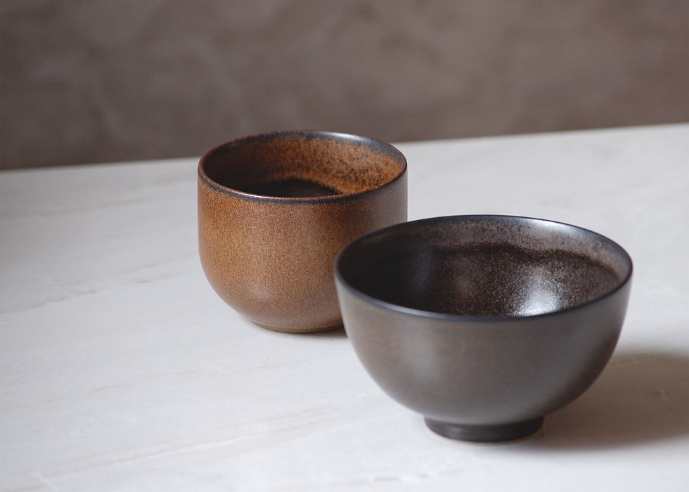 Thumbnail: High view of a minimalist, brown, rustic ceramic cup and brown bowl on a white marble surface with dark background.
