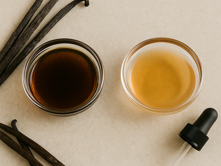 Two small glass bowls side by side, one with dark amber vanilla extract and the other with lighter essence, surrounded by vanilla pods and a dropper.