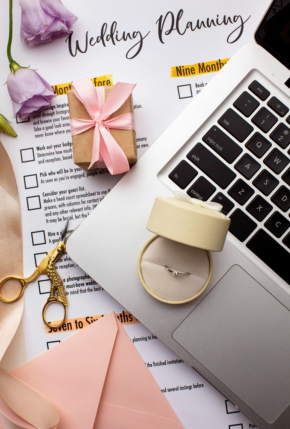 Wedding planning checklist, ring, gift, and laptop.