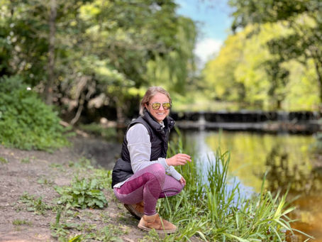 A girl sitting by the river smiling happily.