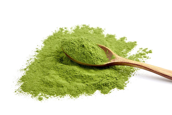 Freeze dried young wheatgrass powder in wooden spoon isolated on white background. Vegan f