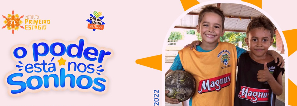 Um menino sorrindo segurando uma bola de futebol com o braço esquerdo e com o braço direito abraça outro menino que faz um sinal de "joia" com a mão esquerda em uma quadra de futebol. Ao lado a frase "O poder está nos sonhos".